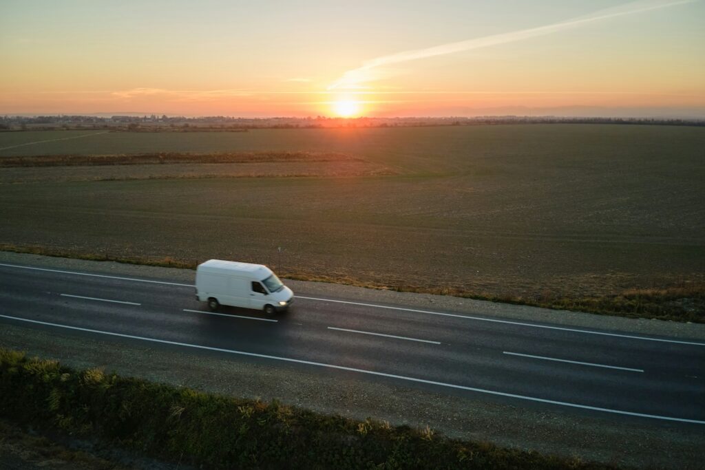 Aerial view of blurred fast moving cargo van driving on highway hauling goods