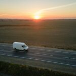 Aerial view of blurred fast moving cargo van driving on highway hauling goods